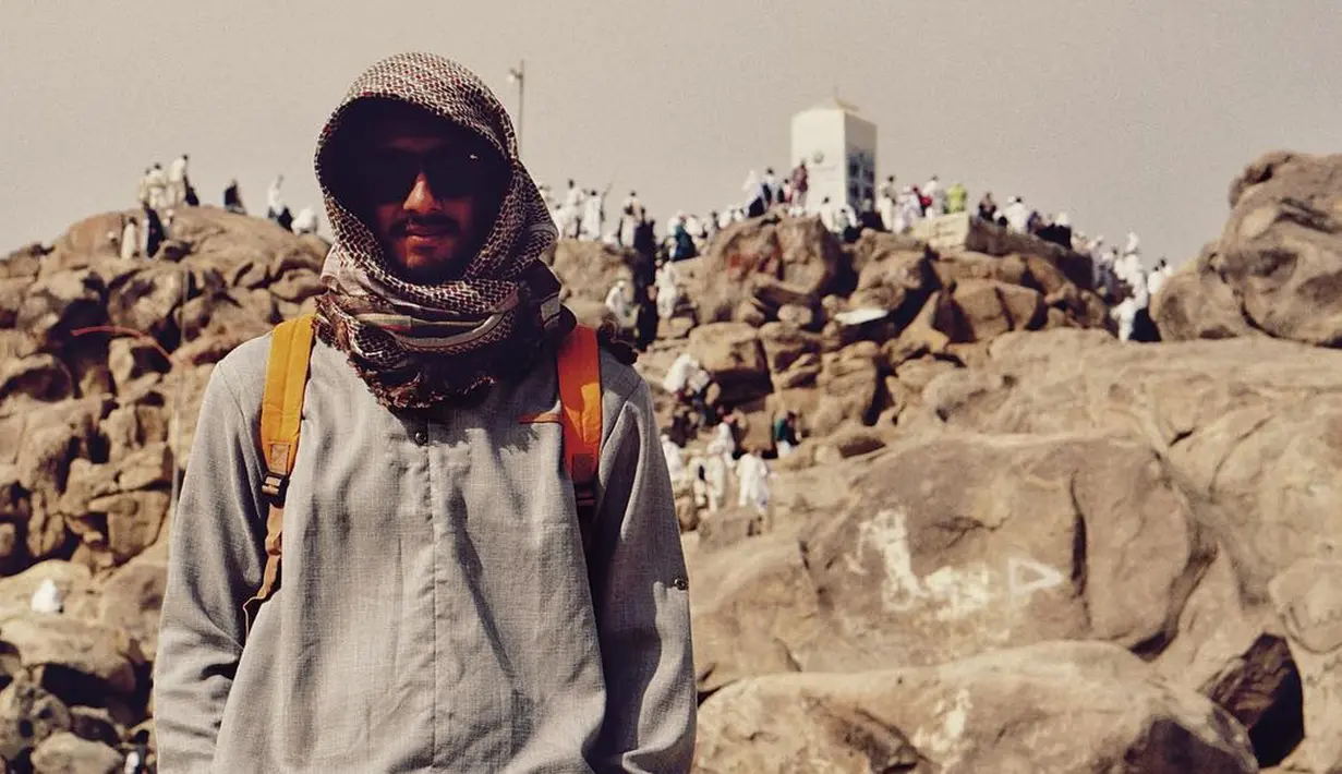 Pakai jubah dan serban ditambah kacamata hitam saat berfoto dengan latar belakang Jabal Rahmah. (Instagram/arya.saloka)