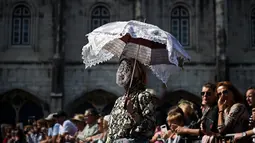 Seorang wanita dari Madamas e Caretos de Torre de Dona Chama mengenakan kostum dan membawa payung saat mengikuti International Festival of the Iberian Mask ke-12 di Belem, Lisbon, Portugal (5/6). (AFP Photo/Patricia De Melo Moreira)