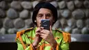 Seorang peserta mengambil gambar saat kegiatan untuk memecahkan rekor dunia dengan jumlah terbesar orang mengenakan pakaian dan bergaya seperti  The Beatles di sebuah taman di Mexico City, Meksiko 28 November 2015. (AFP PHOTO/ALFREDO ESTRELLA)