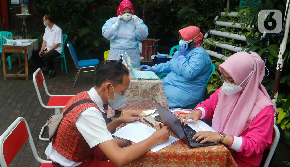 Petugas kesehatan mendata siswa yang akan tes usap PCR di SDN Sudimara Barat 5, Kota Tangerang, Rabu (12/1/2022). Tes usap dilakukan untuk mengantisipasi penyebaran COVID-19 di sekolah setelah mulainya pembelajaran tatap muka kapasitas kelas 100 persen di Kota Tangerang. (Liputan6.com/Angga Yuniar)
