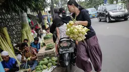 Seorang wanita usai membeli kulit ketupat di Pasar Palmerah, Jakarta, Senin (2/6/2019). Peningkatan drastis dikarenakan banyak warga yang ingin membuat masakan khas Lebaran seperti Opor Ayam yang selalu ditemani ketupat sebagai pengganti lontong. (Liputan6.com/Faizal Fanai)