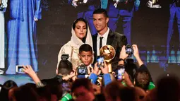 Georgina Rodriguez foto bersama dengan kekasihnya Cristiano Ronaldo dan putranya Cristiano Jr diatas panggung selama Dubai Globe Soccer Awards ke-10 di Dubai (3/1). (AFP Photo/Fabio Ferrari)