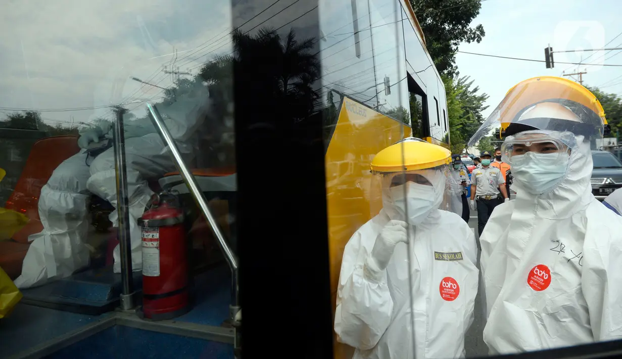 Petugas Dishub memakai baju APD akan menjemput korban yang diduga terjangkit Covid-19 menggunakan bus sekolah di Puskesmas Kebayuran Lama, Jakarta, Senin (6/7/2020). Bus sekolah tersebut selama liburan dibantukan untuk mengangkut pasien Covid-19 ke Wisma Atlet Kemayoran. (merdeka.com/Dwi Narwoko)