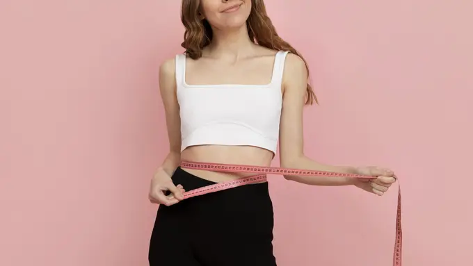 Seorang perempuan sedang mengukur lingkar pinggangnya (Foto Dok: Freepik/freepik)