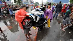 Pengendara motor berusaha menghidupkan motornya yang mati akibat menerjang banjir, Jakarta, Senin (6/2/2015).  Hujan yang turun sejak malam hingga kini membuat sejumlah ruas jalan tergenang air. (Liputan6.com/Faizal Fanani)