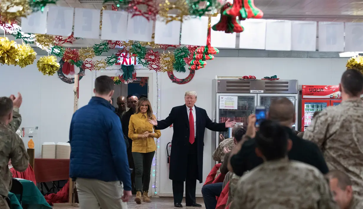 Presiden Donald Trump dan ibu negara Melania Trump mengunjungi pasukan militer Amerika di Pangkalan Udara al Asad, Irak, Rabu (26/12). Kunjungan ini merupakan kunjungan perdananya ke wilayah konflik semasa 2 tahun pemerintahannya. (AP/Andrew Harnik)
