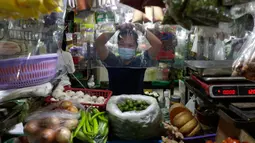 Pedagang menata rambutnya di balik lembaran plastik untuk mencegah virus corona di sebuah pasar di kota Quezon, Filipina, Selasa (22/9/2020). Presiden Filipina Rodrigo Duterte mengatakan telah memperpanjang status masa darurat Covid-19 di negaranya hingga satu tahun ke depan. (AP Photo/Aaron Favila)