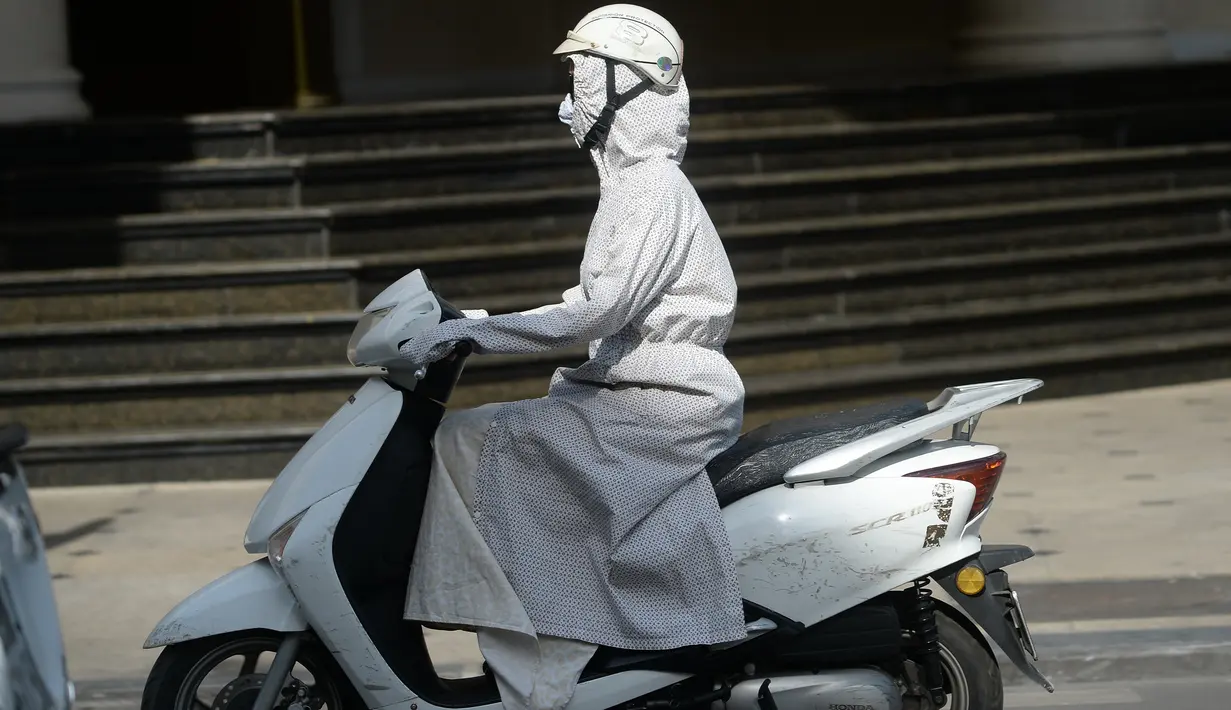 Seorang wanita mengendarai sepeda motor sambil menggunakan pakaian pelindung saat melintasi pusat kota Hanoi, Rabu (15/6). Vietnam menghadapi gelombang panas dengan suhu hingga mencapai 40 derajat celcius. (Hoang DINH NAM/AFP)