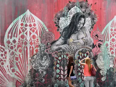 Pengunjung melihat mural yang dibuat oleh seniman Shepard Fairey di kawasan Wynwood, Miami, Florida pada 28 September 2016. Goldman Properties menggelar pameran mural untuk merevitalisasi lingkungan. (AFP PHOTO / Rhona WISE)