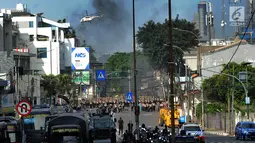 Helikopter water bombing menyiramkan air ke arah ban yang dibakar massa di kawasan Slipi, Jakarta, Rabu (22/5/2019). Air dijatuhkan dari udara ke arah api yang berasal dari ban bekas. (merdeka.com/Arie Basuki)