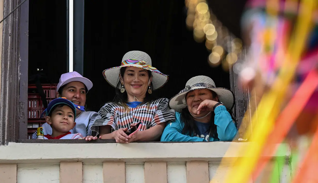 Orang-orang menyaksikan para peserta yang bergembira saat mengambil bagian dalam parade "Nyanyian untuk Bumi" selama Karnaval Kulit Hitam dan Kulit Putih di Pasto, Kolombia pada tanggal 3 Januari 2024. (JOAQUIN SARMIENTO/AFP)