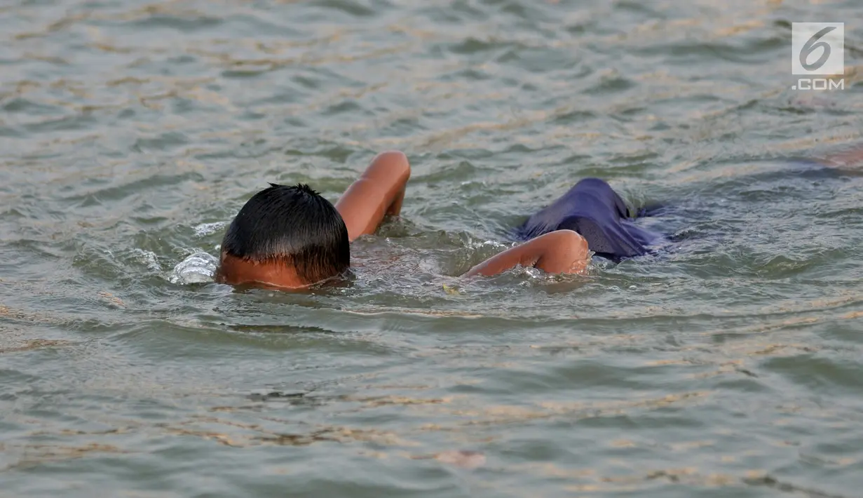 Anak-anak berenang di Danau Sunter, Jakarta, Selasa (23/7/2019). Minimnya fasilitas bermain yang layak dan murah membuat anak-anak nekat berenang di Danau Sunter. (merdeka.com/Iqbal Nugroho)