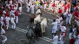 Para peserta menghindar dari kejaran banteng selama Festival San Fermin di Pamplona, Spanyol, Senin (9/7). (JAIME REINA/AFP)