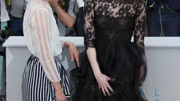 Aktris Emma Stone (kanan) ditemani Parker Posey berpose sambil memegangi roknya yang tersibak oleh angin, jelang pemutaran film Irrational Man, di Festival Film Cannes di Perancis, Jumat (15/5/2015). (REUTERS/Yves Herman)