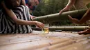 Pengunjung bersiap menikmati langsung minuman beralkohol yang telah disimpan di dalam batang bambu selama beberapa bulan di Hutan Yibin, China pada 30 Juli 2016. (AFP Photo/Fred Dufour)