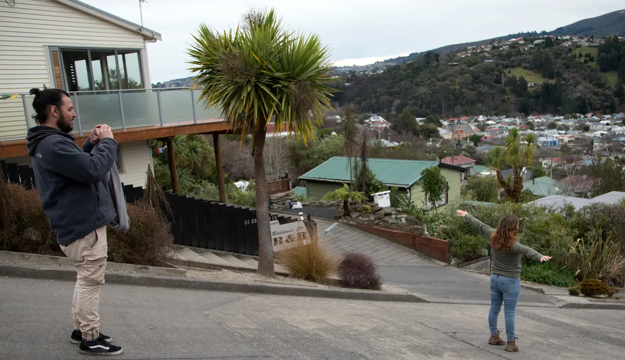 Wisatawan berfoto di tengah Baldwin Street, yang terkenal dengan jalan paling curam di dunia, di kota Dunedin, Selandia Baru, 26 Agustus 2017. Baldwin Street dikenal sebagai jalan paling curam di dunia menurut Guinness World Records. (AP Photo/Mark Baker)