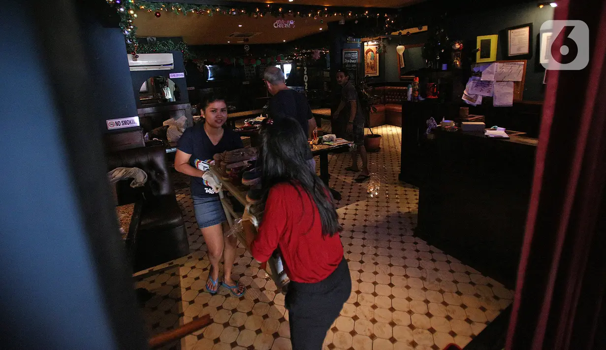 Pegawai membersihkan sisa-sisa banjir di salah satu bar di kawasan Kemang Raya, Jakarta, Kamis (2/1/2020). Para pegawai mulai membersihkan ruangan yang terendam air pascabanjir yang melanda Kemang Raya. (Liputan6.com/Herman Zakharia)
