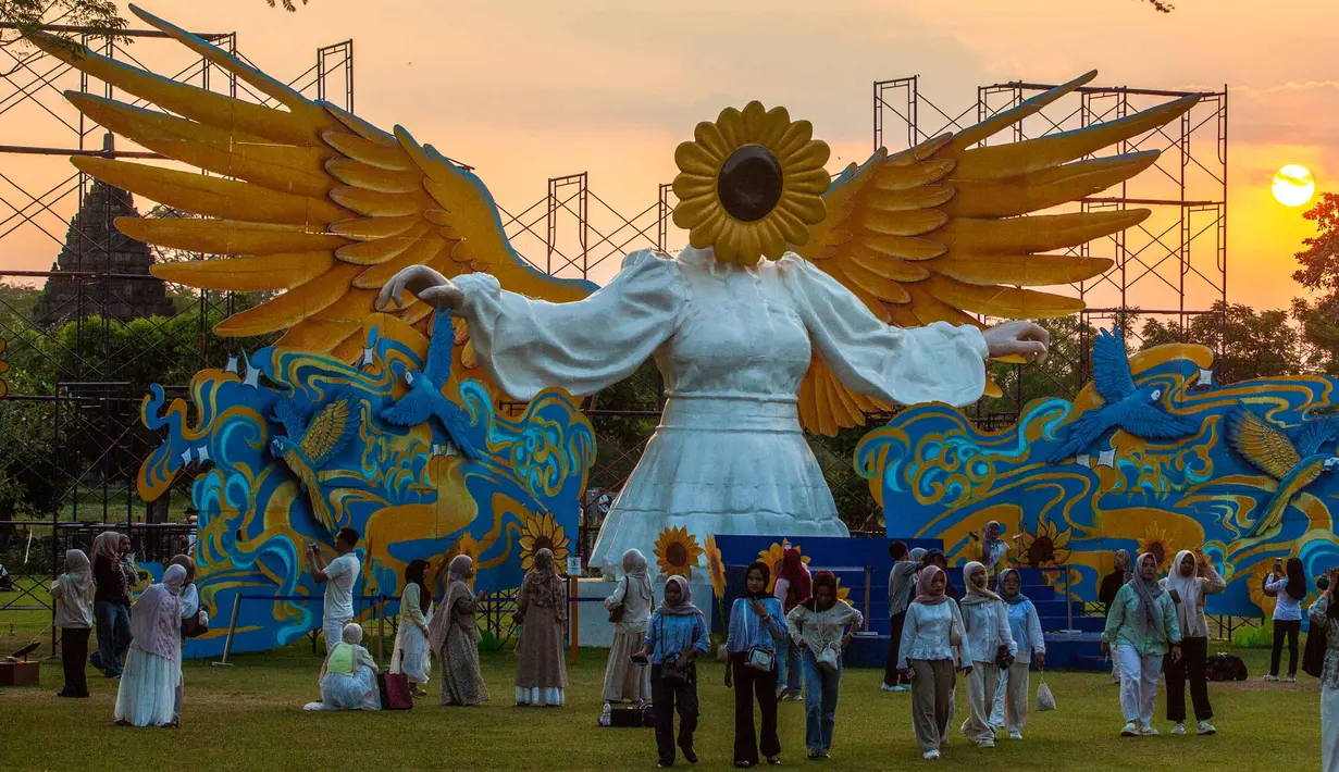 Orang-orang berkumpul di depan "Sunflower Angel", instalasi seni fiberglass setinggi sembilan meter karya seniman lokal Arrofi Ramadhan, di Candi Prambanan, kompleks candi Hindu abad ke-9 yang terdaftar sebagai Situs Warisan Dunia UNESCO, Sleman, Yogyakarta, pada Sabtu 6 Juni 2026. (DEVI RAHMAN/AFP)