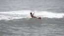  Dengan bertelanjang dada, anak nelayan ini menuju ke tengah laut mencari titik ombak yang siap melesatkan papan selancarnya (Liputan6.com/Faizal Fanani)