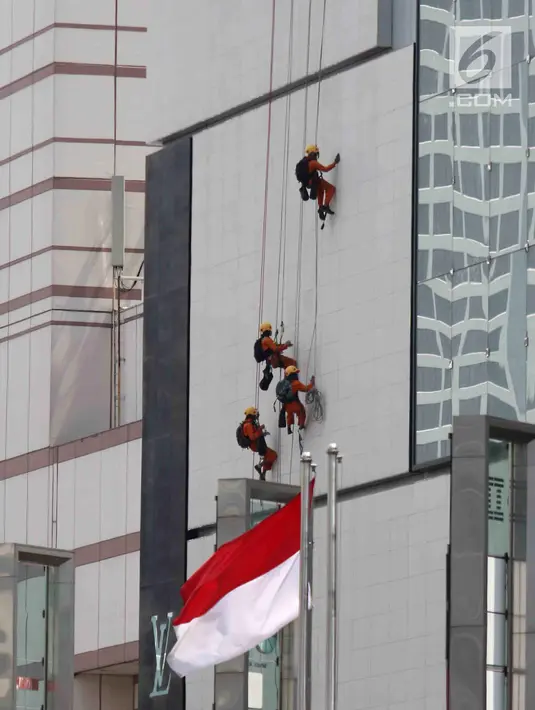 Pekerja membersihkan salah satu gedung bertingkat di Bundaran Hotel Indonesia, Jakarta, Rabu (14/3). BPJS Ketenagakerjaan mengeluarkan nilai klaim Rp 971 miliar sepanjang 2017.  (Liputan6.com/Angga Yuniar)