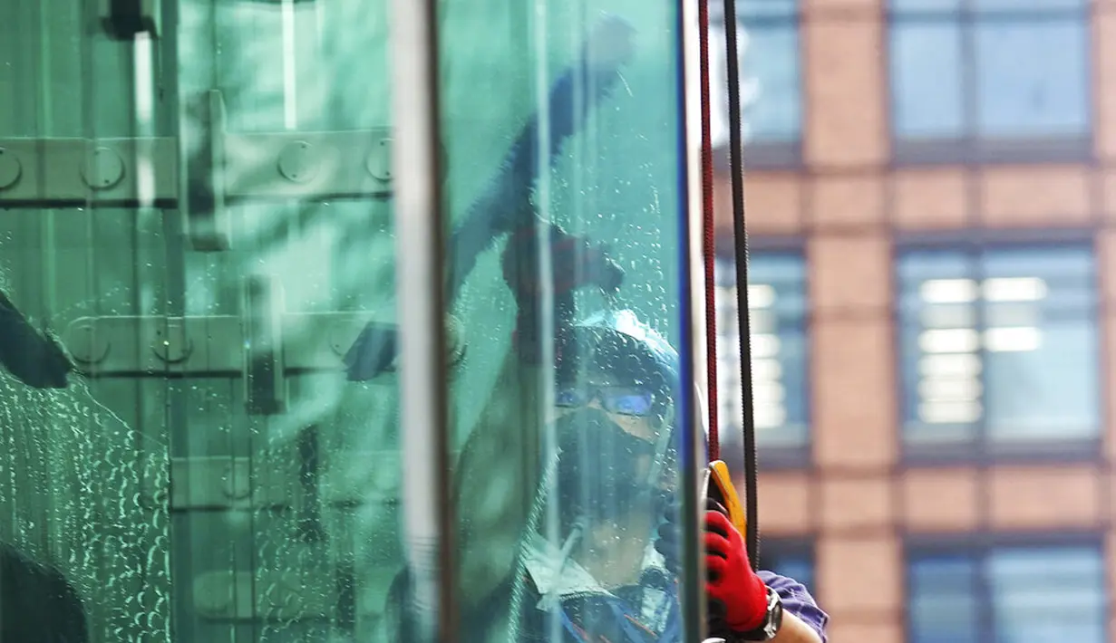 Seorang pekerja yang mengenakan masker untuk membantu mengekang penyebaran COVID-19 menyeka jendela sebuah gedung di Tokyo, Jepang, Senin (2/11/2020). Tokyo mengonfirmasi lebih dari 80 kasus baru COVID-19 pada 2 Oktober 2020. (AP Photo/Eugene Hoshiko)