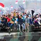 Warga membawa bendera merah putih saat menaiki tank TNI menyaksikan HUT TNI ke-70 di Dermaga Indah Kiat, Cilegon, Banten, Senin (5/10/2015). HUT TNI Ke-70 ditandai atraksi tempur tiga matra TNI Angkata Darat, Laut dan Udara. (Liputan6.com/Faisal Fanani)