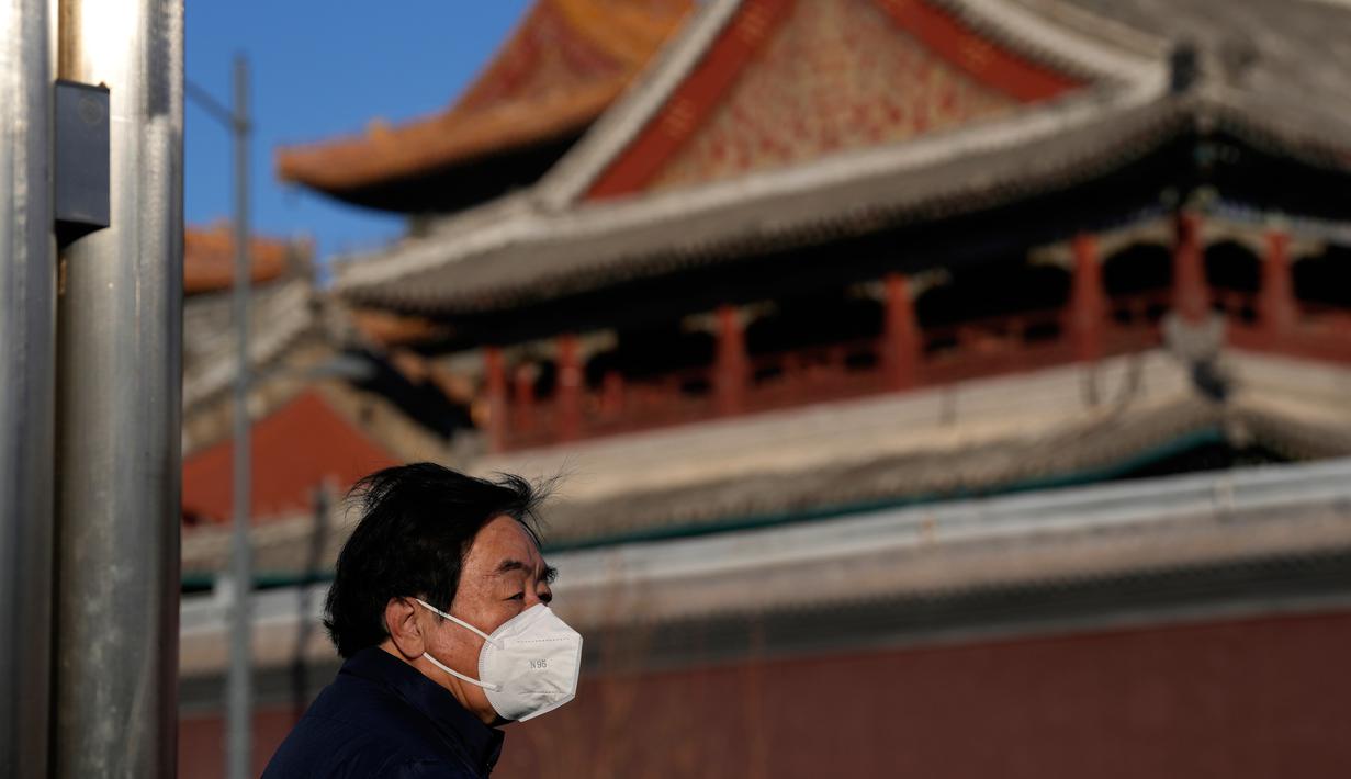 Seorang warga yang mengenakan masker berdiri dekat Kuil Lama di Beijing, China, 27 Desember 2022. Perusahaan menyambut baik keputusan China untuk mengakhiri karantina bagi pelancong dari luar negeri sebagai langkah penting untuk menghidupkan kembali aktivitas bisnis yang merosot, sementara Jepang mengumumkan pembatasan pengunjung saat infeksi melonjak. (AP Photo/Ng Han Guan)