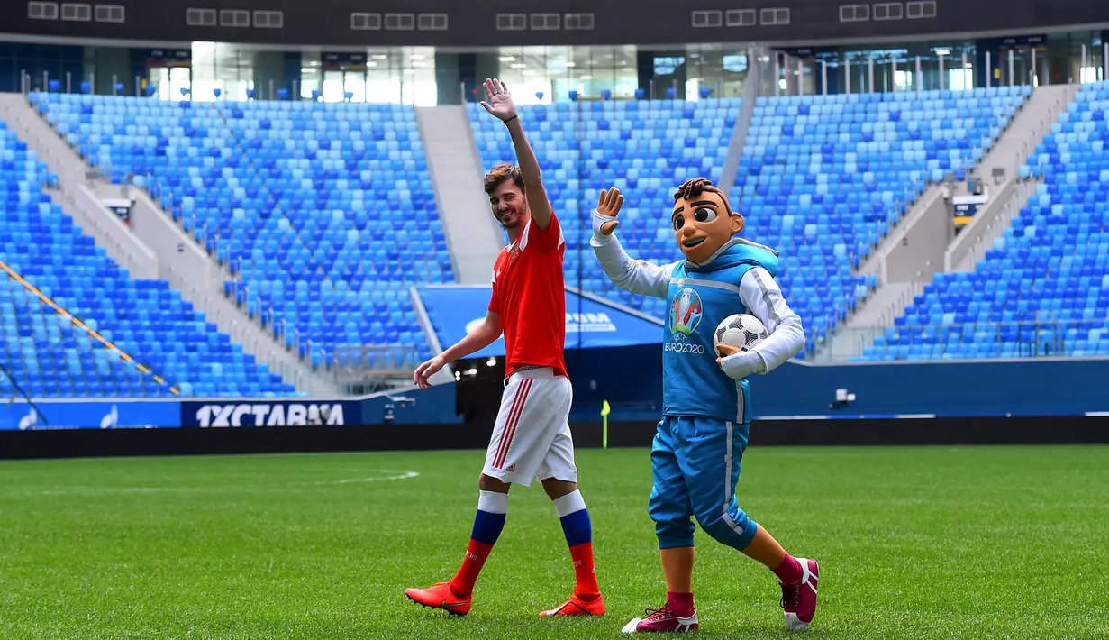 Maskot resmi Piala Eropa 2020, Skillzy dan pemain Rusia, Alexander Erokhin menyapa penonton saat presentasi di Stadion Saint Petersburg, Rusia (27/3). Kota Saint Petersburg akan menyelenggarakan empat pertandingan termasuk pertandingan perempat final selama UEFA Euro 2020. (AFP Photo/Olga Maltseva)