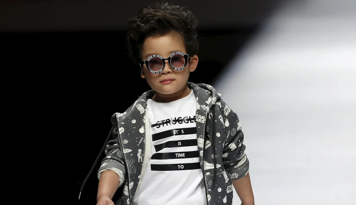 Seorang anak dengan lucunya berjalan diatas catwalk mengenakan busana kreasi dari Ting Zu pada China Fashion Week,  Cina , (27/3). Busana kreasi Ting Zu ini memang diperuntukkan oleh anak-anak. (REUTERS / Kim Kyung - Hoon)
