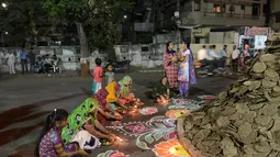 Warga bersiap di dekat Holika untuk melakukan ritual, Ahmedabad, India, Minggu (12/3). Bagi warga setempat Holika melambangkan kemenangan kebaikan atas kejahatan. (AFP PHOTO / SAM PANTHAKY)