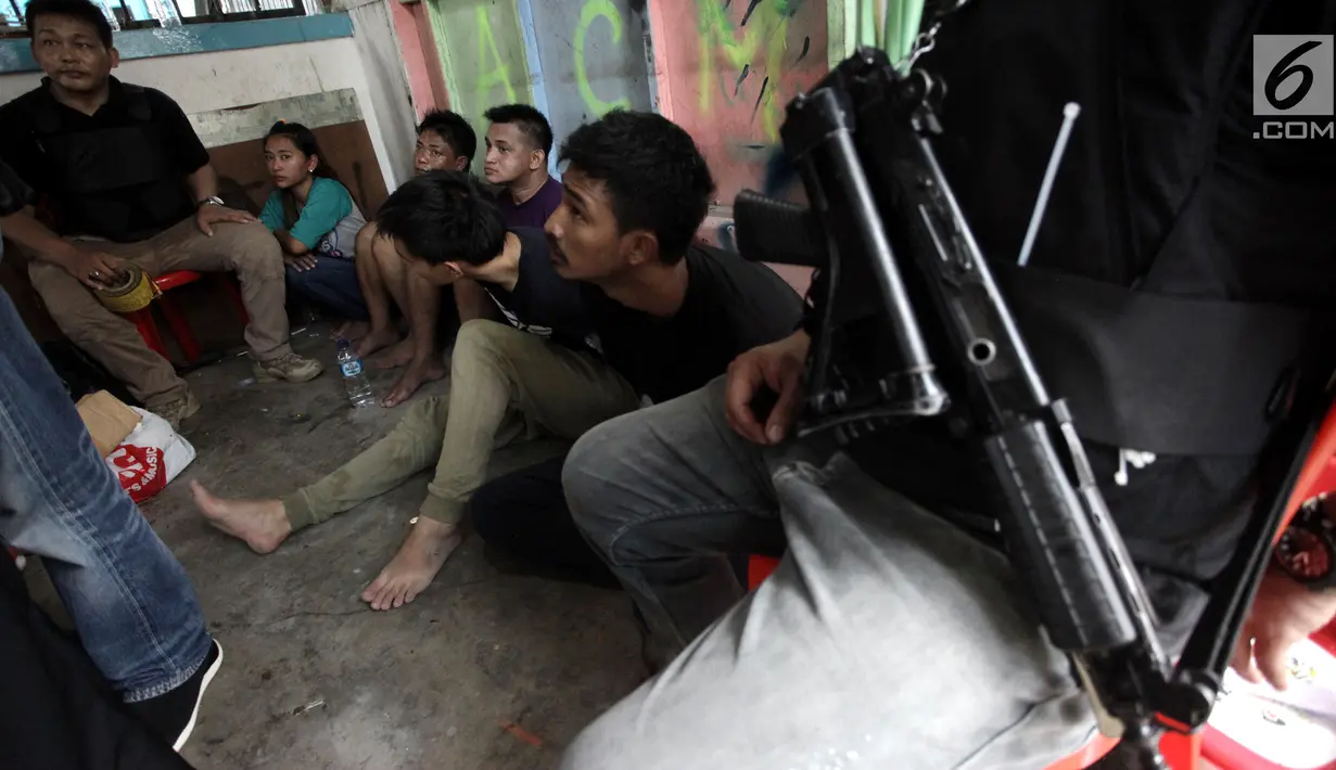 Sejumlah tersangka tertunduk lesu usai polisi menggerebek peredaran narkoba di kawasan Kampung Ambon, Cengkareng, Jakarta Barat, Rabu (24/1). Dalam penggerebekan tersebut polisi menangkap enam tersangka. (Liputan6.com/Arya Manggala)