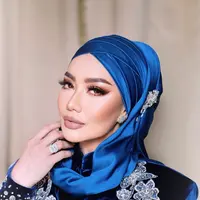 Reza menutup penampilannya dengan hijab lilit biru satin dengan aksesori silver dan makeup yang bold [@rezaartameviaofficial]