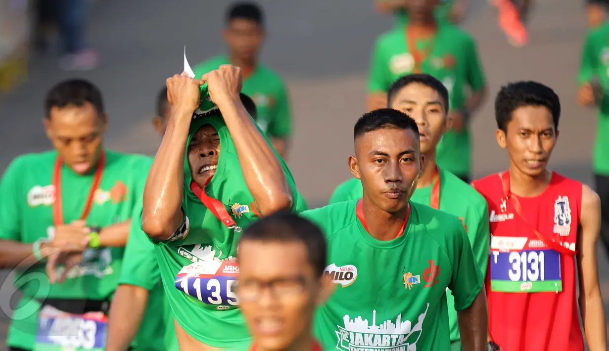 Seorang peserta melepas kaosnya usai memasuki garis finish dalam lomba lari Jakarta International 10K 2015 di Silang Monas, Jakarta, Minggu (31/5/2015). (Liputan6.com/Helmi Afandi)