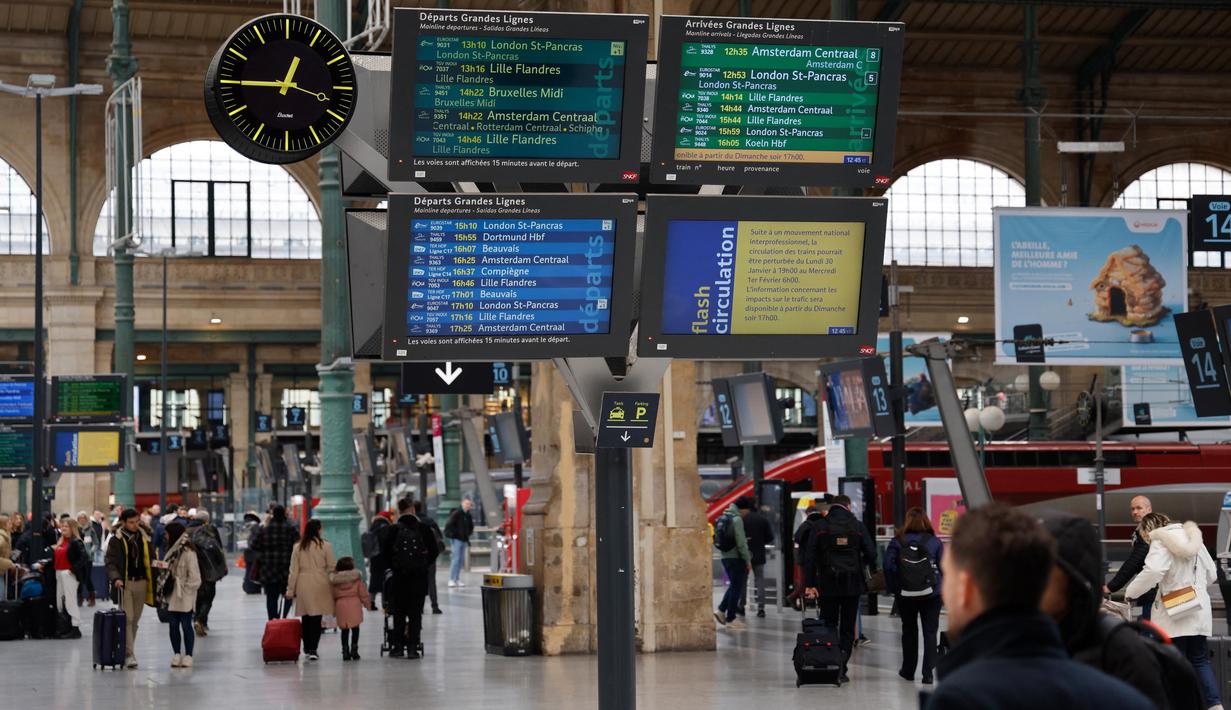 Sejumlah pelancong berjalan melewati layar informasi saat lalu lintas terganggu di stasiun kereta Gare du Nord pada hari kedua pemogokan nasional dan protes terhadap rencana reformasi pensiun pemerintah di Paris, Selasa (31/1/2023). Prancis bersiap-siap menghadapi gangguan transportasi utama, dengan pemogokan massal dan protes yang akan melanda negara tersebut untuk kedua kalinya. (Ludovic MARIN/AFP)