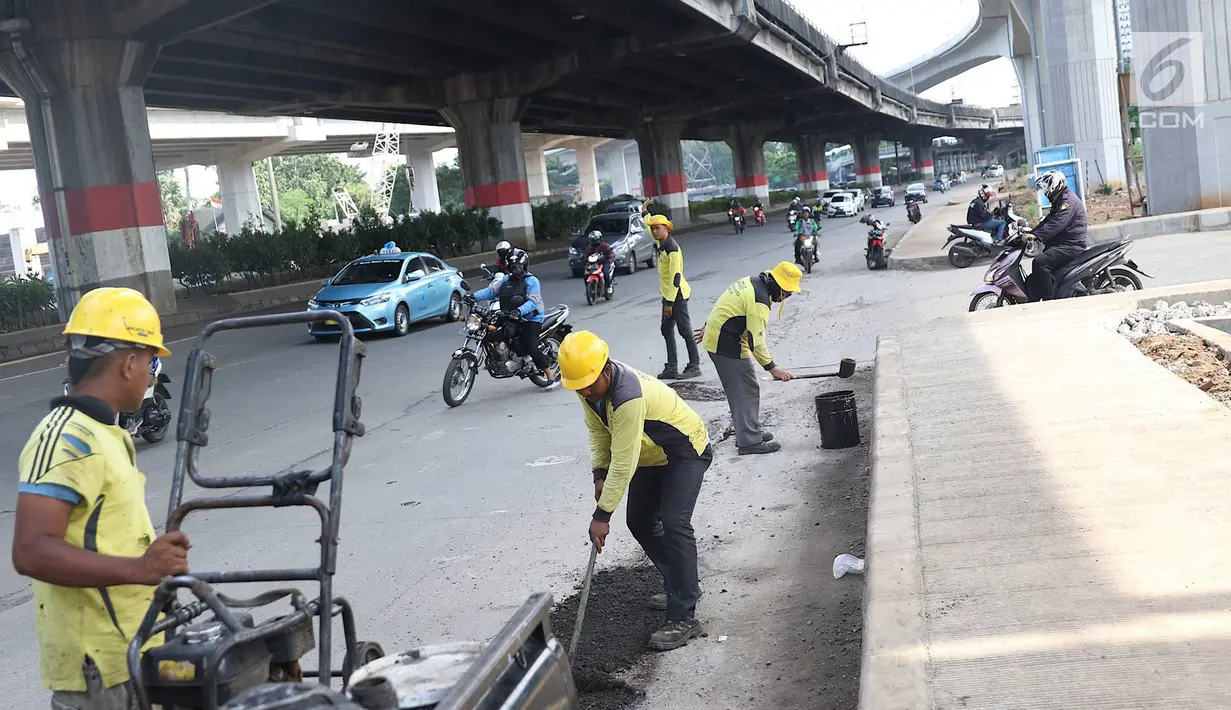 Petugas menambal lubang pada jalan yang rusak di kawasan Jatinegara, Jakarta, Kamis (7/2). Musim hujan yang mengguyur Jakarta selama beberapa waktu terakhir meninggalkan kerusakan pada sejumlah ruas jalan di Ibukota. (Liputan6.com/Immanuel Antonius)