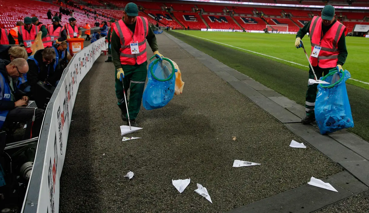 Petugas mengumpulkan pesawat terbang kertas yang dilemparkan suporter selama pertandingan Inggris melawan Slovenia di kualifikasi Piala Dunia 2018 di stadion Wembley, London, (5/10). (AFP Photo/Adrian Dennis)