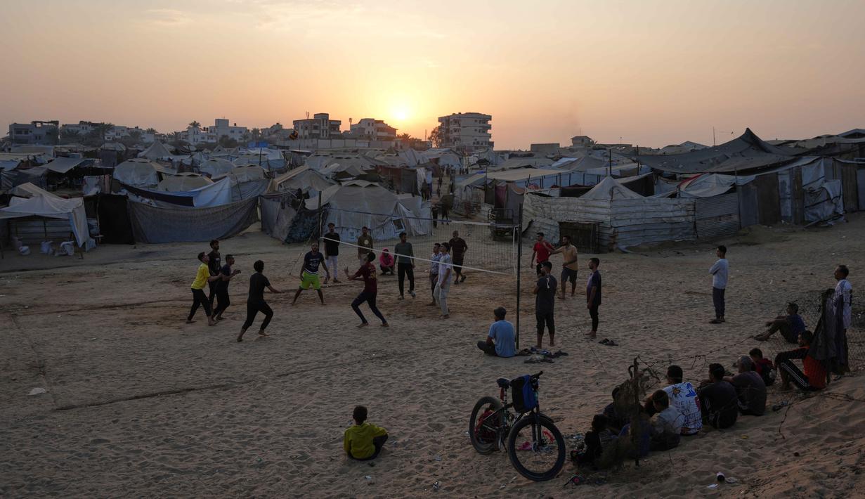 Anak-anak muda Palestina bermain voli di kamp tenda pengungsian di Zawayda, Jalur Gaza tengah, Selasa 4 November 2025. Perang yang berlangsung selama dua tahun lebih, sejak pada 7 Oktober 2023, telah menghancurkan 81% bangunan di Gaza, termasuk rumah sakit, sekolah, tempat penampungan, dan fasilitas penting lainnya. (AP Photo/Abdel Kareem Hana)