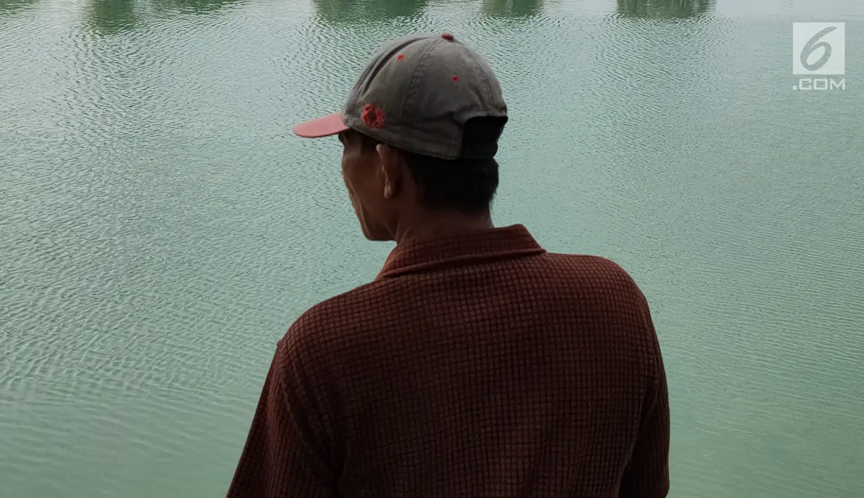Seorang warga mengamati Danau Sunter yang berwarna hijau di Jakarta Utara pada Senin (8/7/2019). Lamanya musim kemarau di Ibu kota menjadi penyebab danau tersebut berubah warna menjadi hijau yang dipicu oleh pertumbuhan lumut. (Liputan6.com/Immanuel Antonius)