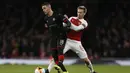 Bek Arsenal, Nacho Monreal mencoba menghentikan Hatem Ben Arfa pada leg kedua,babak 16 besar Liga Europa yang berlangsung di Stadion Emirates, London, Jumat (15/3). Arsenal menang 3-0 atas Rennes. (AFP/Ian Kington)