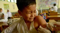 Siswa MIN Ulee Kareng menutup matanya saat mendapat vaksinasi anti virus difteri yang diberikan petugas Kesehatan di Banda Aceh, Aceh, Selasa (20/2). Dari catatan Dinkes, difteri kerap menyerang manusia kisaran usia 4 - 28 tahun. (CHAIDEER MAHYUDDIN/AFP)