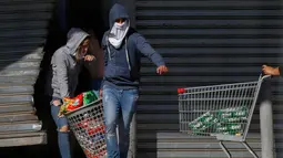 Warga menjarah sebuah supermarket di Puente Alto, wilayah metropolitan Santiago, Chile, Minggu (20/10/2019). Bentrokan pecah di Santiago setelah dua orang tewas ketika sebuah supermarket dibakar ketika protes terhadap kondisi ekonomi dan ketidaksetaraan sosial. (DRAGOMIR YANKOVIC/ATON CHILE/AFP)