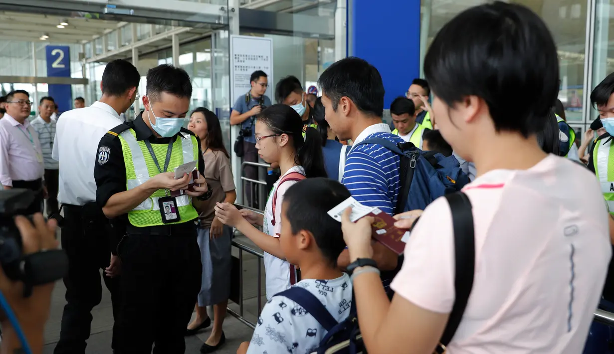 Petugas keamanan memeriksa informasi penerbangan para pelancong di gerbang pintu masuk utama bandara di Hong Kong, Rabu (14/8/2019). Bandara Hong Kong kembali membuka penerbangan keberangkatan pada Rabu pagi setelah sempat lumpuh selama dua hari terakhir akibat demonstrasi. (AP/Vincent Thian)