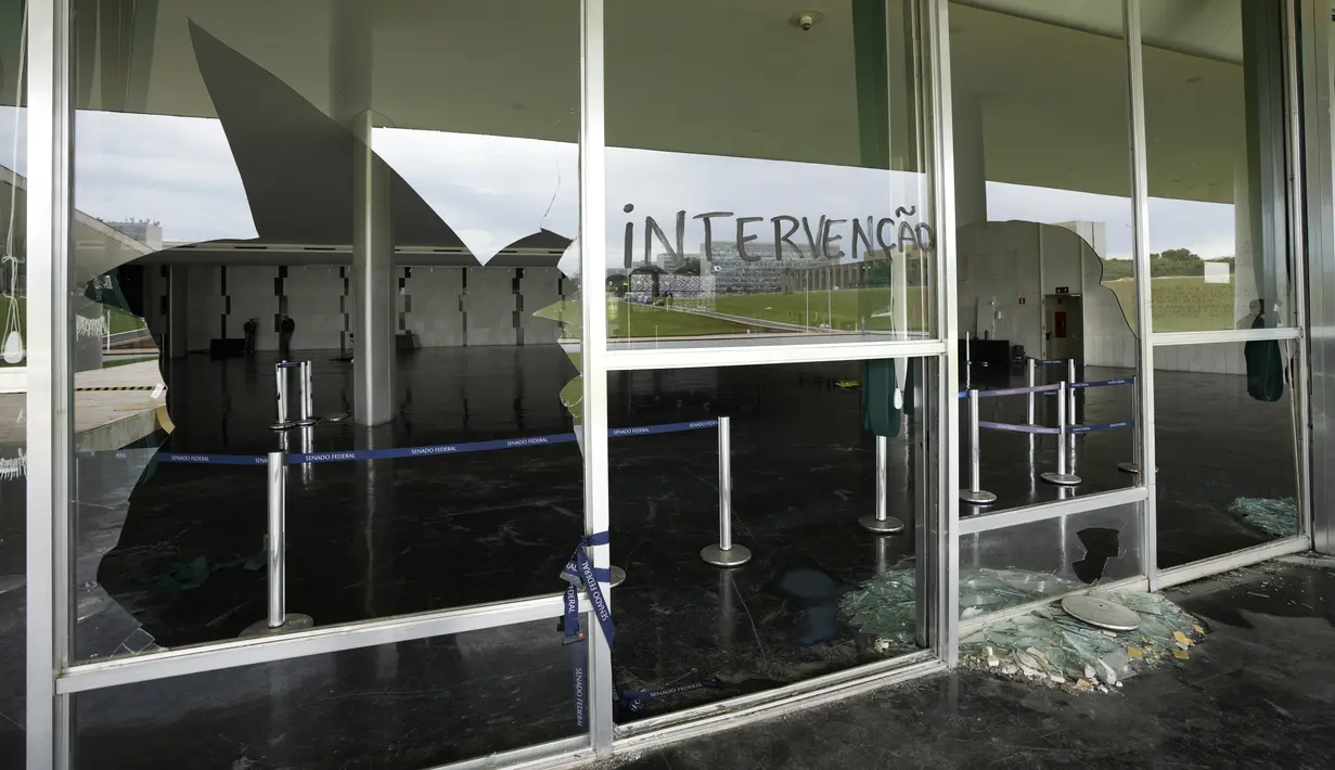 Kata Portugis "Intervensi" menutupi pecahan kaca di Senat setelah Gedung Kongres diserbu oleh pendukung mantan Presiden Brasil Jair Bolsonaro di Brasilia, Senin (9/1/2023). Kericuhan itu terjadi satu pekan setelah Presiden Luiz Inácio Lula da Silva dilantik. (AP Photo/Eraldo Peres)