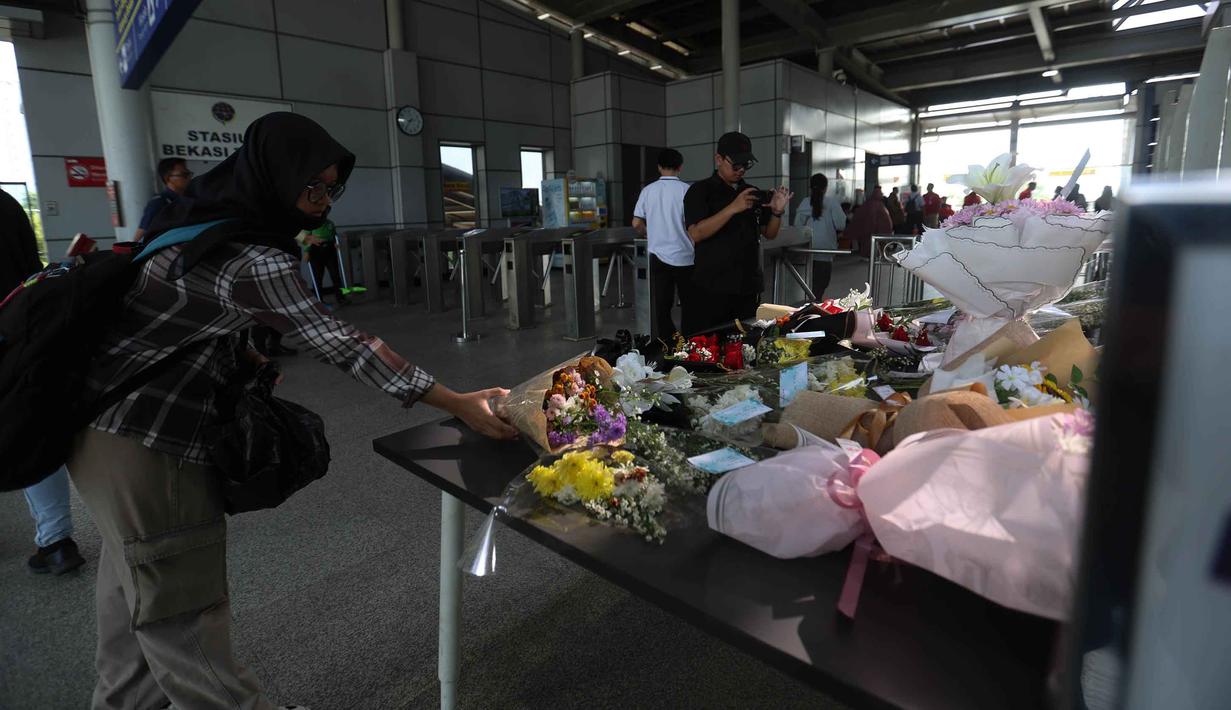 Sejumlah bunga tersusun rapi, ada pula yang dilengkapi kartu ucapan serta kertas berisi tulisan tangan yang diselipkan di antara rangkaian bunga. Tampak dalam foto, warga meletakkan karangan bunga di dekat pintu masuk peron Stasiun Bekasi Timur, Bekasi, Jawa Barat, Kamis (30/4/2026). (Kapanlagi.com/Budy Santoso)
