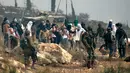 Tentara Israel berdiri ketika pemukim Israel bertopeng melemparkan batu ke arah demonstran Palestina (tak terlihat) yang berkumpul selama demonstrasi menentang pembangunan pos terdepan Israel di dekat desa Palestina, Ramallah, Tepi Barat, Kamis (17/10/2019). (JAAFAR ASHTIYEH/AFP)