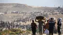 Orang-orang berjalan membawa tas-tas berisi bantuan kemanusiaan yang mereka terima di pusat distribusi yang dikelola oleh Yayasan Kemanusiaan Gaza (GHF) yang didukung Ameriks Serikat dan Israel, di koridor Netzarim, Nuseirat, Jalur Gaza tengah, pada 26 September 2025. (Eyad BABA/AFP)