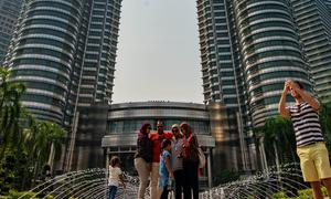 Sejumlah orang memotret di depan Menara Kembar Petronas, Kuala Lumpur, Malaysia, 18 Maret 2016. Kombinasi antara gedung pencakar langit dan situs bersejarah serta perpaduan harmonis beragam budaya semakin memperkaya pesona khas dari Kuala Lumpur. (Xinhua/Chong Voon Chung)