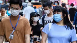 Pejalan kaki mengenakan masker sebagai tindakan pencegahan Covid-19 saat berjalan di Hong Kong (13/5/2020). Dua orang di Hong Kong dinyatakan positif Covid-19, mengakhiri perjalanan 24 hari tanpa kasus baru yang mulai melonggarkan peraturan jarak sosial. (AFP/Anthony Wallace)