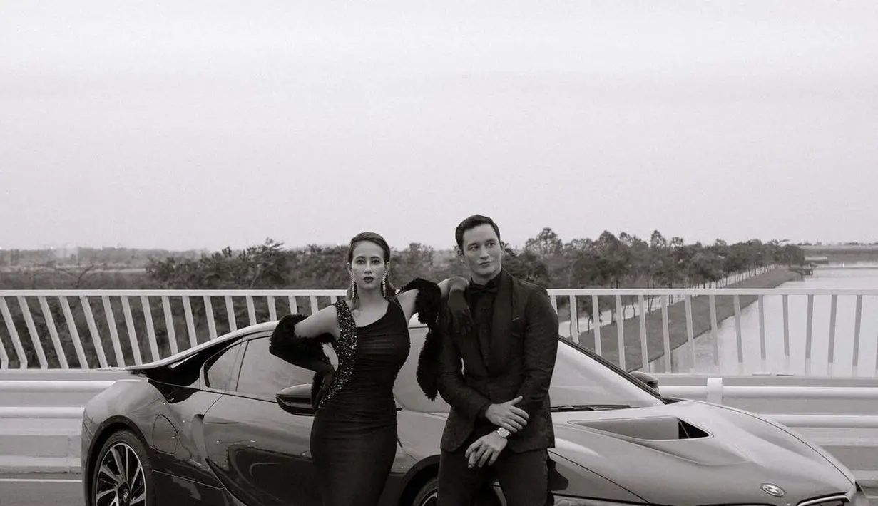 Kesan mewah yang klasik terlihat dari potret hitam putih Mike Lewis yang mengenakan setelan jas di depan mobil mewah. Berdiri di sampingnya, Janisaa tampil berkelas dengan dress satin dan bulu-bulu (instagram/mikelewis)