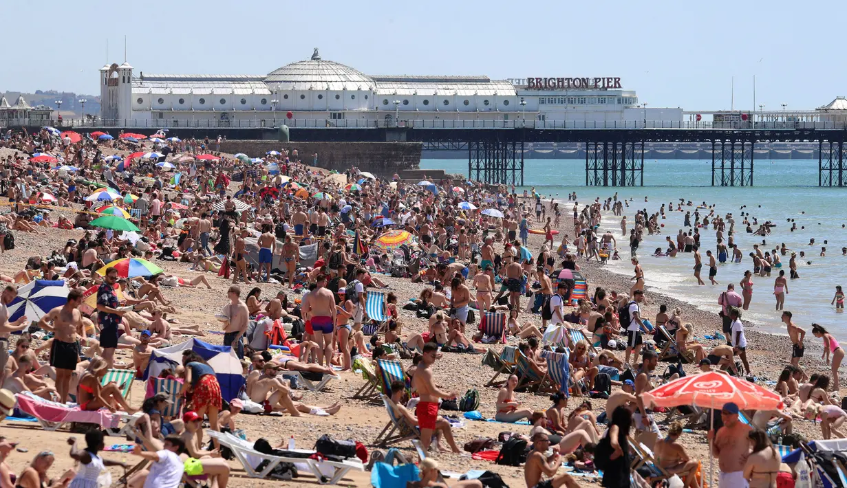 Kerumunan pengunjung berkumpul di pantai untuk menikmati hari terpanas tahun ini di Brighton, Inggris, Kamis (25/6/2020). Pantai tersebut diserbu warga Inggris, setelah masa pelonggaran pembatasan sosial akibat covid-19 dan pembatasan perjalanan Eropa. (Gareth Fuller/PA via AP)